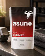Asuno Alpha Gummies pouch on a home gym bench with a dumbbell and towel