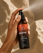 Hand spraying Asuno Self Tanning Oil onto skin — fine-mist pump for even application